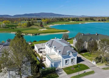 Luftaufnahme der luxuriösen Villa am Seeufer mit angrenzendem Golfplatz und malerischer Landschaft.
