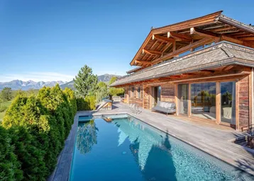 Luxuriöses Chalet mit privatem Außenpool und atemberaubendem Bergblick unter blauem Himmel.