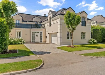 Elegante Villa mit gepflegtem Vorgarten, gepflasterter Auffahrt und integrierter Garage.