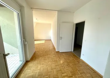 Helles Zimmer mit Parkettboden und Zugang zu einem Balkon, ideal als Wohnbereich nutzbar.