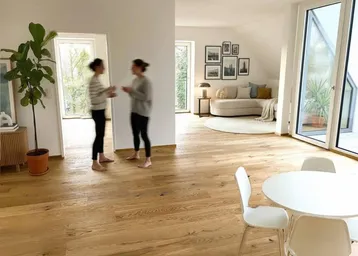 Heller, offener Wohn- und Essbereich mit Holzboden, Dachschrägen und Zugang zur Terrasse.