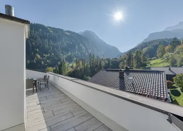 Sonnige Dachterrasse mit Bergblick und Sitzgelegenheiten, ideal zum Entspannen im Freien.