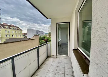 Balkon mit Fliesenboden und Blick auf die umliegende Bebauung und den Himmel.