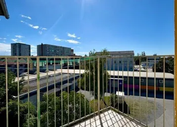 Sonniger Balkon mit Metallgeländer und weitem Blick über die städtische Umgebung.