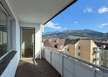 Geräumiger Balkon mit Holzboden und weitem Blick auf die umliegende Berglandschaft.