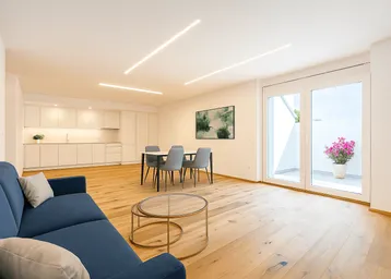 Moderner offener Wohn-Essbereich mit integrierter Küche, Holzboden und Zugang zur Terrasse.