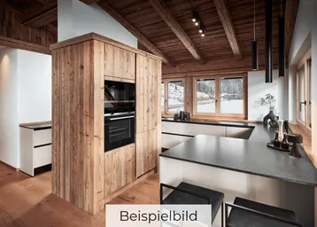 Moderne Küche mit Holzelementen, dunkler Arbeitsplatte und Blick auf die verschneite Landschaft.