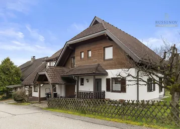 Ansicht des Hauses von vorne mit traditioneller Holzverkleidung und Satteldach.