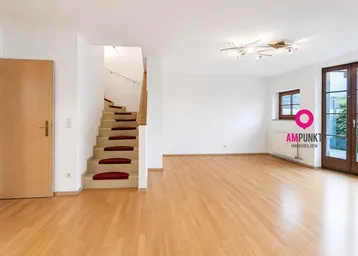 Helles, leeres Wohnzimmer mit Parkettboden, Treppe und Zugang zur Terrasse.