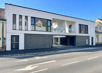 Moderne Wohnanlage mit weißer Fassade, großen Fenstern und integrierten Garagen.