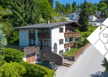 Freistehendes Einfamilienhaus mit Garage, Balkonen und gepflegter Gartenanlage in Hanglage.