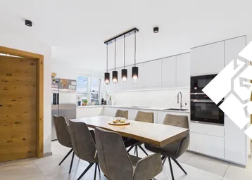 Moderne offene Küche mit Essbereich, weißen Schränken und Holztisch, ideal für gesellige Mahlzeiten.