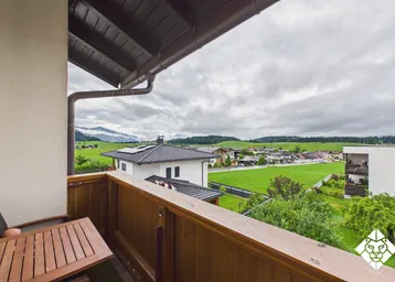 Balkon mit Holzboden und weitem Blick über grüne Wiesen und die umliegende Landschaft.