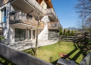 Moderne Wohnanlage mit Holzfassade, Balkonen und einer gepflegten Rasenfläche im Vordergrund.