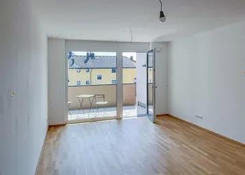 Helles Wohnzimmer mit Parkettboden und Zugang zu einem sonnigen Balkon, ideal für Entspannung.