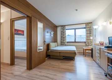 Gemütliches Schlafzimmer mit Holzwänden, Laminatboden und Blick auf die Umgebung.
