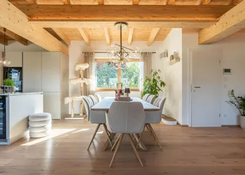 Helles Esszimmer mit Holzbalkendecke, Parkettboden und Blick in den Garten.