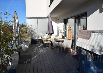 Geräumiger Balkon mit Holzboden, Sitzgelegenheiten und Pflanzen, ideal zum Entspannen im Freien.