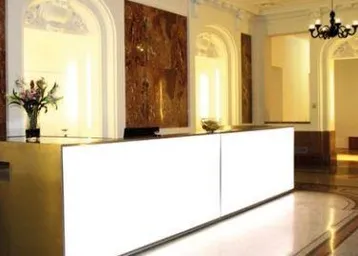 Elegante Empfangshalle mit modernem Tresen, Marmorboden und klassischer Deckenbeleuchtung, die einen luxuriösen Eindruck vermittelt.