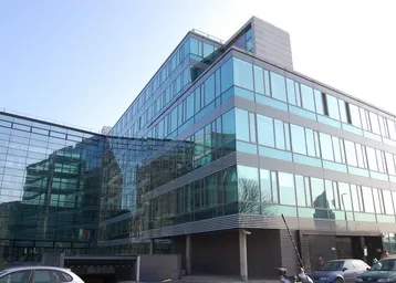 Modernes Bürogebäude mit einer beeindruckenden Glasfassade, die das Sonnenlicht reflektiert und eine zeitgemäße Architektur zeigt.