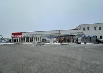 Außenansicht des Quester-Gebäudes mit großem Parkplatz und leichter Schneedecke im Winter.
