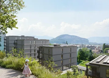 Panoramablick auf die Wohnanlage mit mehreren Gebäuden und einer weiten Aussicht auf die umliegende Landschaft und Berge.