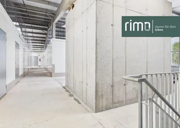 Langer Gang in einer modernen Lagerhalle mit Betonwänden und Metallkonstruktion, ideal für Self-Storage.