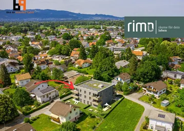 Luftaufnahme eines modernen Wohngebäudes in einer grünen Wohngegend mit Bergblick.