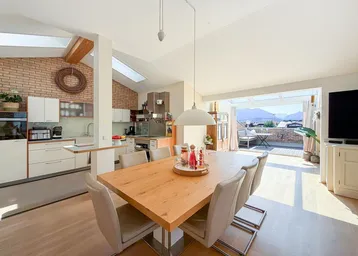 Heller offener Wohn- und Essbereich mit moderner Küche, Holzboden und Zugang zur Dachterrasse.