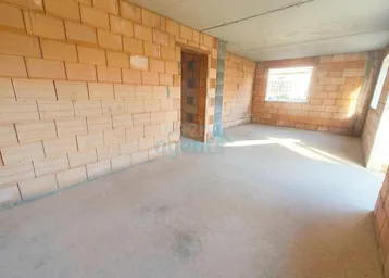 Unfertiger Innenraum mit unverputzten Ziegelwänden und Betonboden, bereit für den Ausbau.