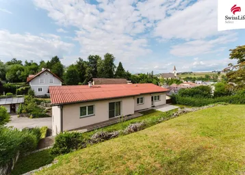 Rückansicht des Hauses mit rotem Ziegeldach und weitem Blick über die Landschaft und ein Dorf.