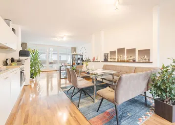 Heller offener Wohn- und Essbereich mit integrierter Küche, Parkettboden und Zugang zur Terrasse.