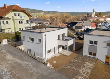 Moderne Neubau-Doppelhaushälfte mit Flachdach und Blick auf die umliegende Ortschaft.