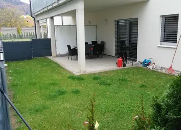 Gepflegter Gartenbereich mit überdachter Terrasse und Balkon im Obergeschoss.