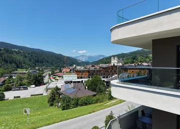 Geräumiger Balkon mit Glasbrüstung und weitem Blick auf die umliegende Berglandschaft und Stadt.