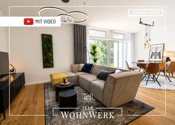 Moderner offener Wohn- und Essbereich mit beigem Sofa, Holzboden und großen Fenstern mit Blick ins Grüne.