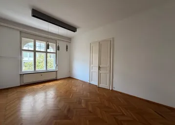Helles Zimmer mit Fischgrätparkettboden, hohen Decken und großen Fenstern.