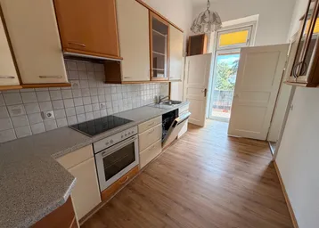 Funktionale Küche mit Einbauschränken, Spülmaschine und Zugang zum Balkon.