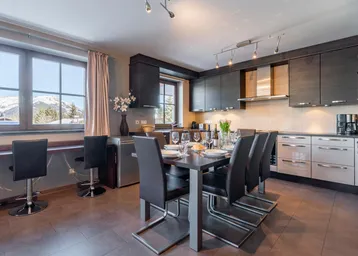 Moderne Küche mit Essbereich, Bergblick und dunklen Holzschränken, ideal für gesellige Mahlzeiten.