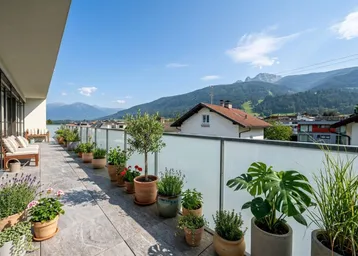Lange Terrasse mit vielen Pflanzen, Sitzgelegenheiten und weitem Blick auf die Berge.