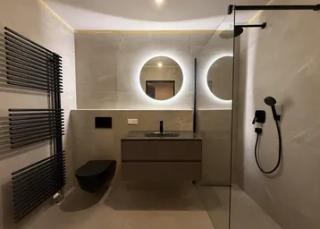 Modernes Badezimmer mit begehbarer Dusche, schwebendem Waschtisch und beheiztem Handtuchhalter in Grautönen.