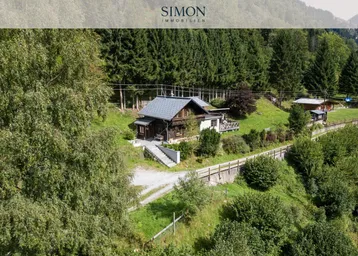Charmantes Chalet in idyllischer alpiner Umgebung, umgeben von Wald und grünen Wiesen.