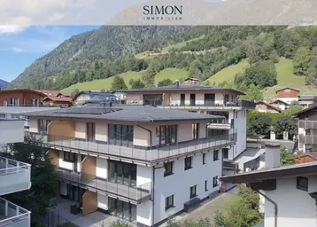 Moderne Apartmentgebäude mit Balkonen und Flachdächern, eingebettet in eine grüne Berglandschaft.