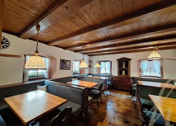 Traditioneller Essbereich mit Holzbalkendecke, rustikalen Möbeln und gefliestem Boden, der eine gemütliche Atmosphäre schafft.