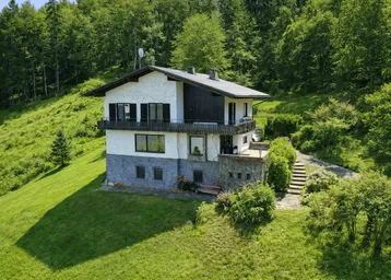 Charmantes Haus in Hanglage, umgeben von üppigem Grün und Wald, mit Balkon und Terrasse.