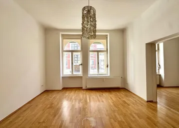 Helles, leeres Zimmer mit Parkettboden und zwei hohen Bogenfenstern, bereit zur individuellen Gestaltung.