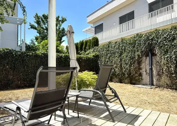 Entspannungsbereich im Garten mit Holzterrasse, Liegestühlen und grüner Hecke.