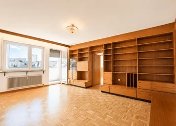 Helles Wohnzimmer mit Parkettboden, großen Fenstern und einer umfangreichen Holzregalwand im Vintage-Stil.