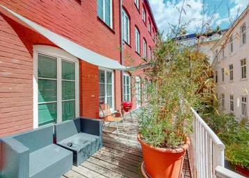 Geräumige Terrasse mit Sitzgelegenheiten, Pflanzen und einem Grill, umgeben von roten Backsteinmauern.