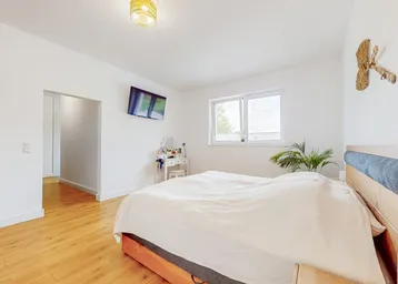 Helles Schlafzimmer mit Holzboden, Doppelbett und Fenster mit Blick ins Grüne.